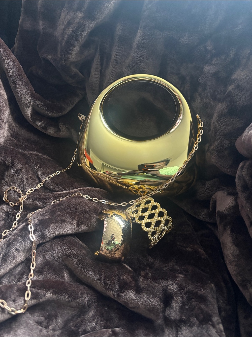Gold Metallic Round Crossbody Bag with Chain with a set of Gold tone bangles.